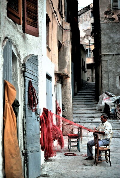 Homme réparant un filet de pêche en Corse